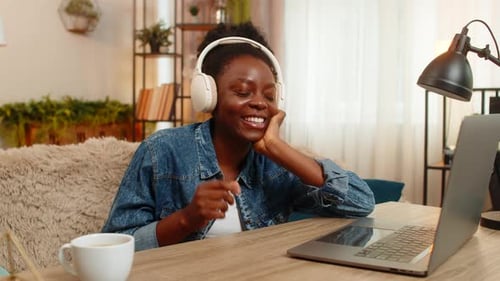 Woman Chatting on Laptop with Headphones in Home
