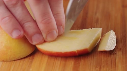 Le chef coupe des pommes avec un couteau sur une planche à découper pour préparer un dessert, une compote ou un jus de fruits