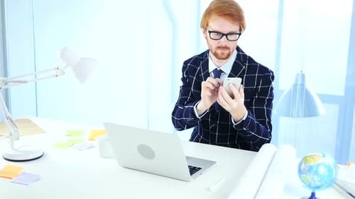 Redhead Man Using Smartphone for Online Browsing Designer