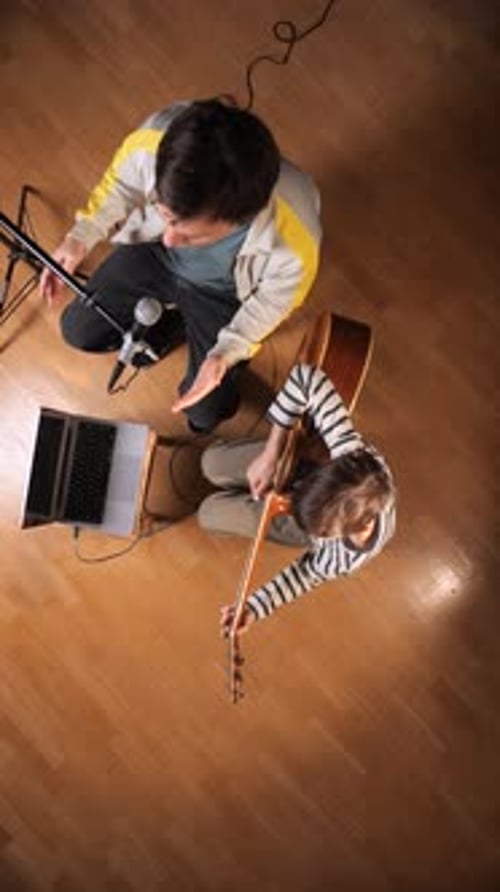 Vertical Video Father and Son Collaborate in a Home Studio Playing Acoustic Guitar and Singing Into