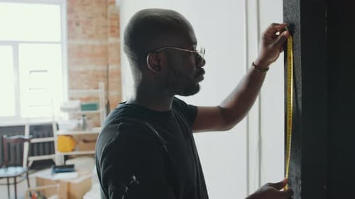 African American Man Measuring Door Frame during Home Remodeling