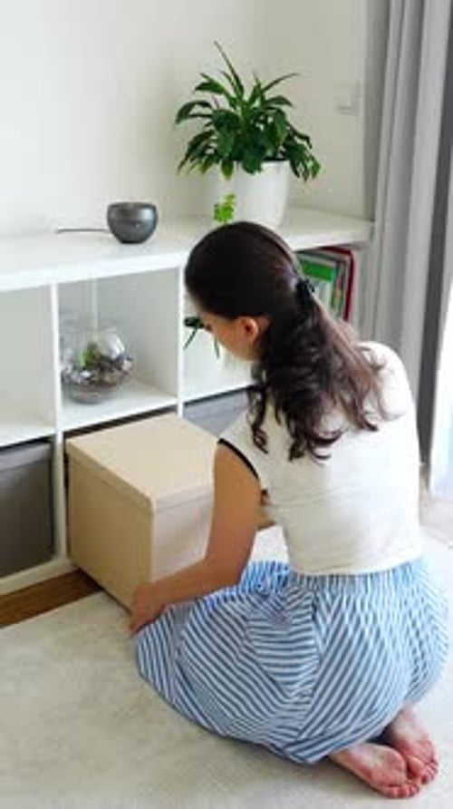 Young Woman Using Storage Box From Shelving System in Home Interior Home Organization and
