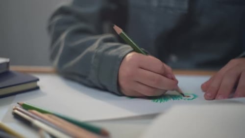 Child Drawing with Colored Pencils on Paper
