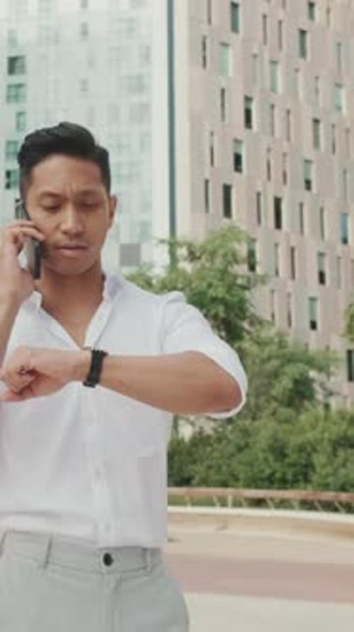 Young businessman walking down the street and talking on smartphone