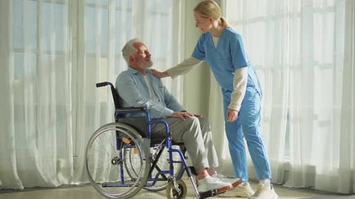 Kind Nurse Talking With Senior Man in Wheelchair