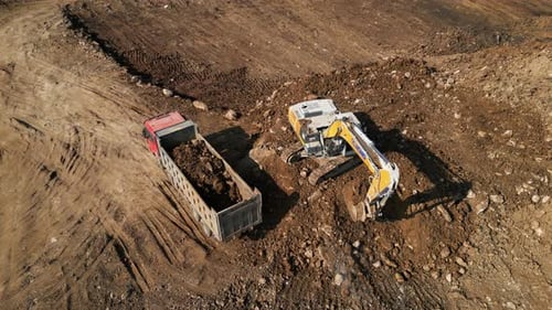 Excavator Loading Dirt Into Truck Aerial View