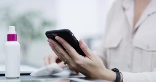 Woman Cleans Smartphone with Sanitizer Spray and Wipe