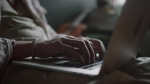 Nahaufnahme der Hände eines unbekannten jungen Mannes, der auf der Laptoptastatur tippt