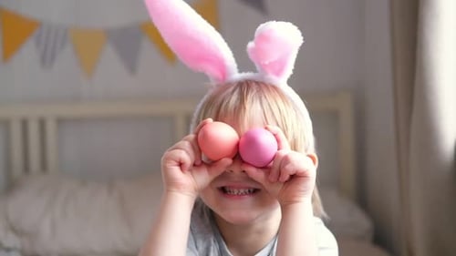 Funny Child Holds Easter Eggs Near the Eyes