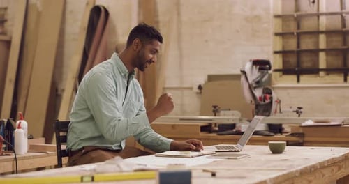 Laptop, Schreiben und Feiern mit einem Schreiner in seiner Werkstatt für Design auf einem kreativen