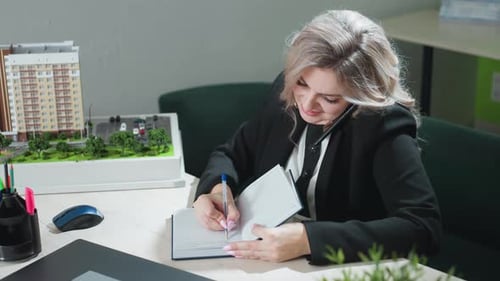 Real Estate Professional Multitasking with Call and Notes in Office