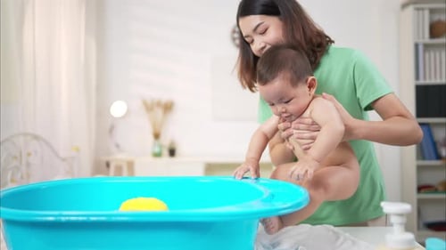 Mother Bathes Smiling Baby in Blue Tub