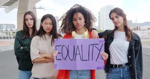 Young Women Looking Seriously at Camera Holding Feminist Sign Saying Equality
