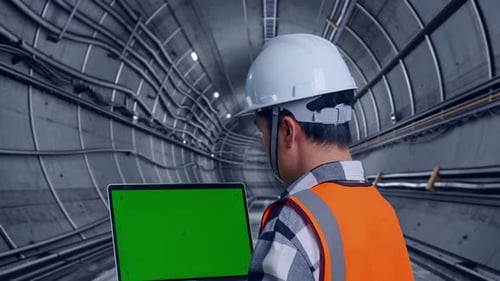 Close Up Back View Of Asian Male Engineer Working On A Green Screen Laptop In Subway Tunnel