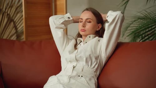 Woman Relaxing on Couch in a Stylish Jumpsuit