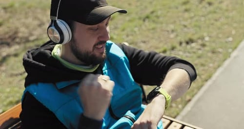 After Running Long Distance Man Sits on Park Bench and Looks at Watch to See How Many Kilometers He