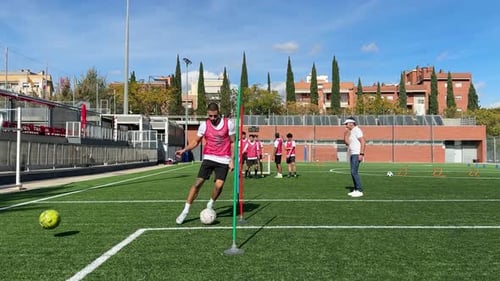 Man Training Children in Soccer on Field
