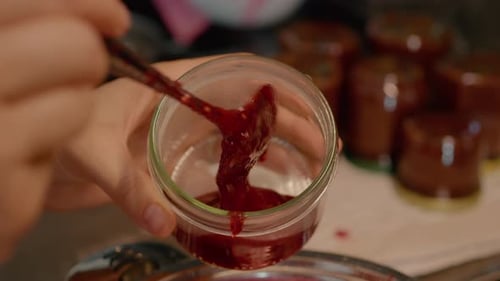 Filling Jars with Homemade Red Jam in Kitchen