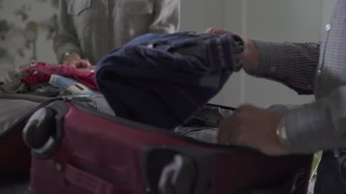 Older couple packing clothes into luggage at home