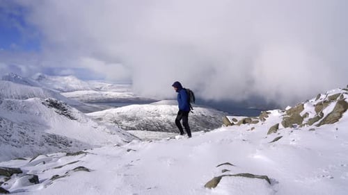 Male hiker walking over the winter mountain landscape in Scotland. Steady shot