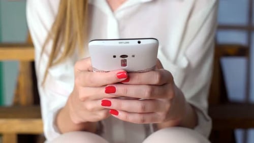 Woman scrolls on her smartphone with red manicure