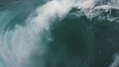 A close up look inside a heavy wave breaking in slow motion along a shallow reef break.