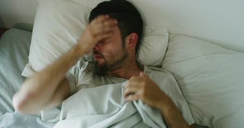 Young Man Awake Lying in Bed Restlessly