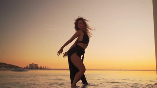 Woman Dancing on Beach at Sunrise