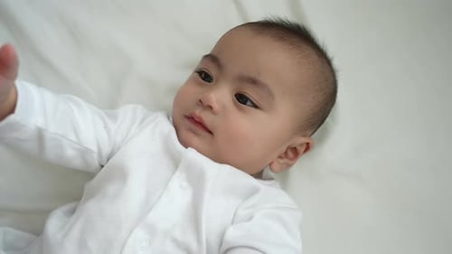 Smiling of newborn baby or cute little lying on a white bed at home.