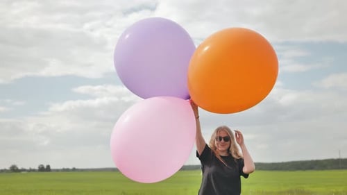 Happy Girl with Big Multicolored Balloons Posing on the Field