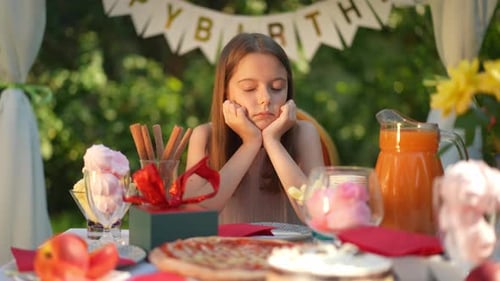 Girl Sits Sadly at Birthday Party