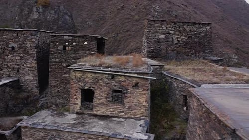 The drone flies around an ancient building made of stone whose roof is overgrown with grass