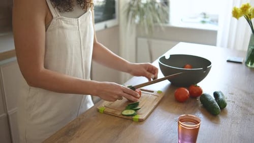 Woman Prepares Fresh Salad in Bright Kitchen