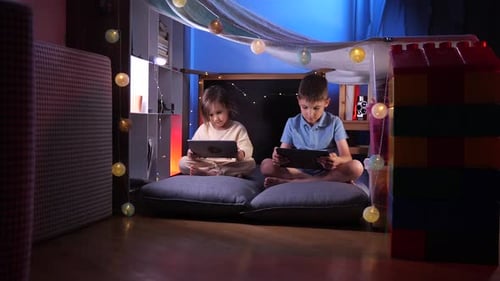 Children Using Tablets in Cozy Blanket Fort at Home