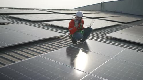 Ein Arbeiter inspiziert das Solarpanel auf dem Dach der Fabrik.