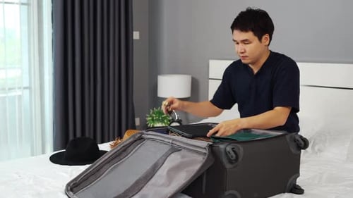 man packing clothes and close the suitcase on bed at home, holiday travel concept
