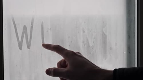 Hand Writing Winter on Steamy Glass Window