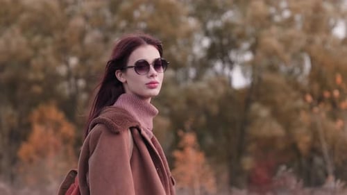 Stylish woman in jacket with autumn leaves background