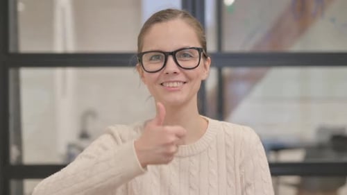 Smiling Woman Giving Thumbs Up in Office
