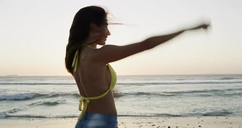 Happy, sunset and woman walking at the beach on holiday, vacation or travel in summer lens flare