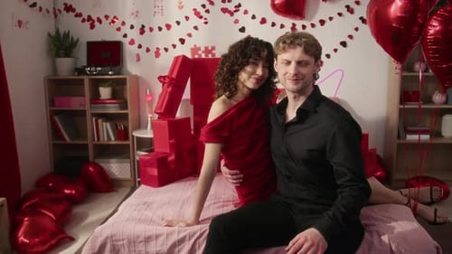 Romantic young couple embraces in bedroom with red decor