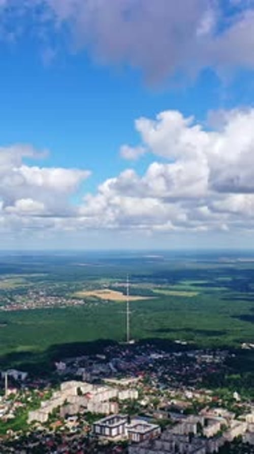 Vue panoramique sur une ville au milieu d'une nature verdoyante. Paysage urbain sous un ciel bleu avec des nuages blancs
.