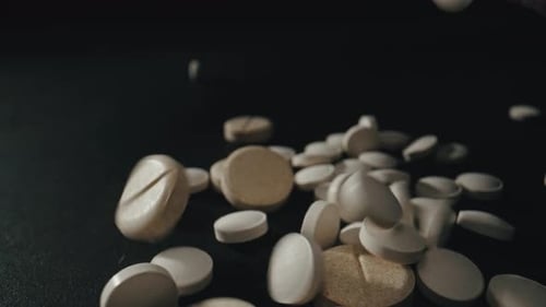 Pills Falling in Slow Motion on Dark Background