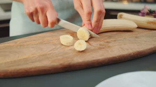 Woman Slicing a Banana on Cutting Board