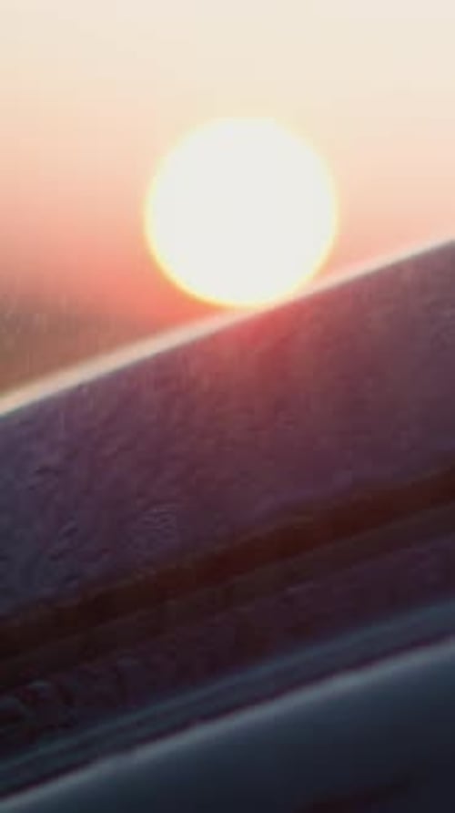 Rain Falls on Car Against Dusk Sun Closeup