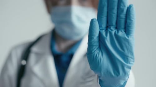 Doctor with Medical Mask Holds up a Hand