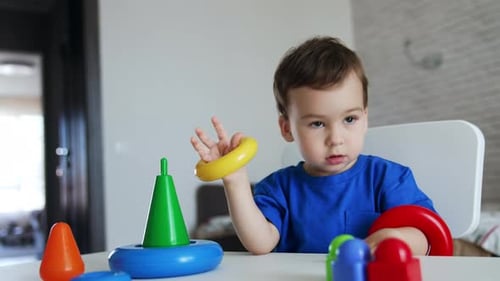 Der kleine Junge legte die Ringe der Spielzeugpyramide auf seine Hände. Ein nettes Kind baut das Spielzeug
zusammen.