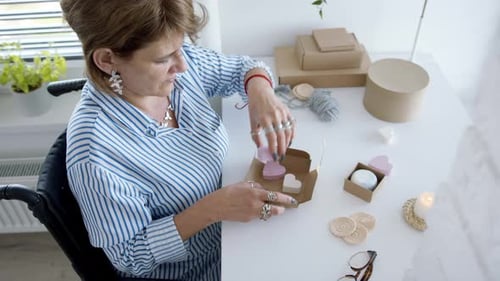 Woman Packages Soap and Heart Ornaments at Desk