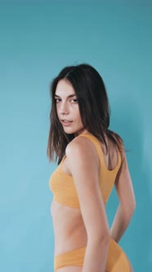 Un beau mannequin en sous-vêtements jaunes pose devant la caméra. Beau corps sexy. Fille sexy en dessous