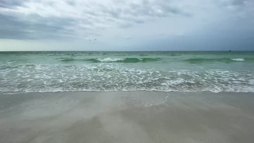 A relaxing day by the side of the ocean on the sandy beach as the waves come rolling in.